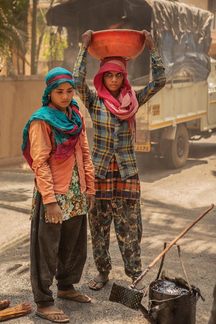 Two women carrying materials at a construction site